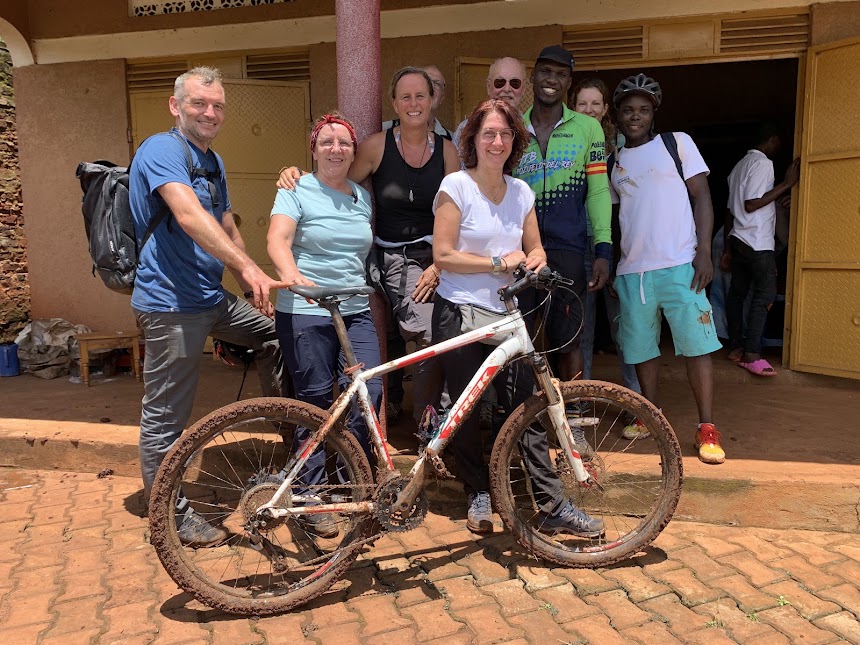 Guests and guide with a mud-covered bicycle after a Kampala wetland ride