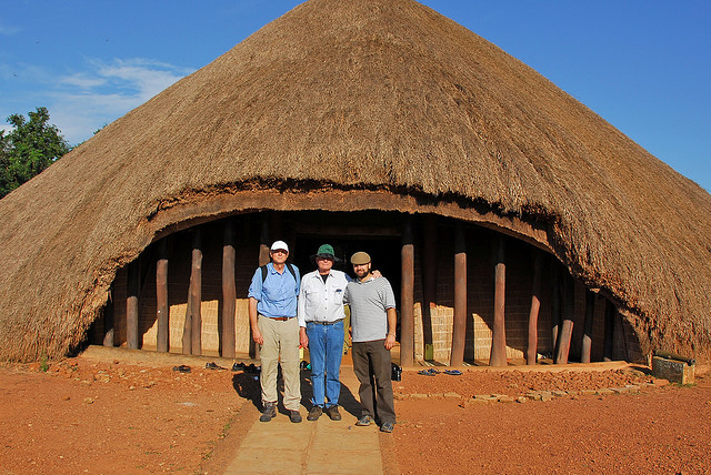 Guests outside a traditional thatched royal building in Uganda